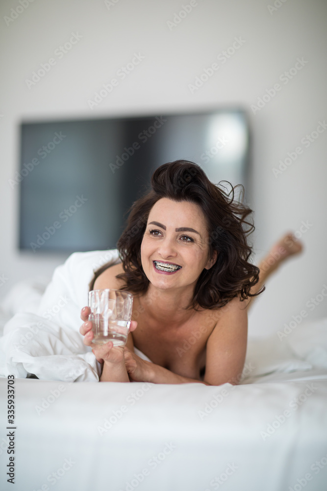 Beautiful young woman drinking water in bed on a lovely morning Beautiful young woman drinking water in bed on a lovely morning