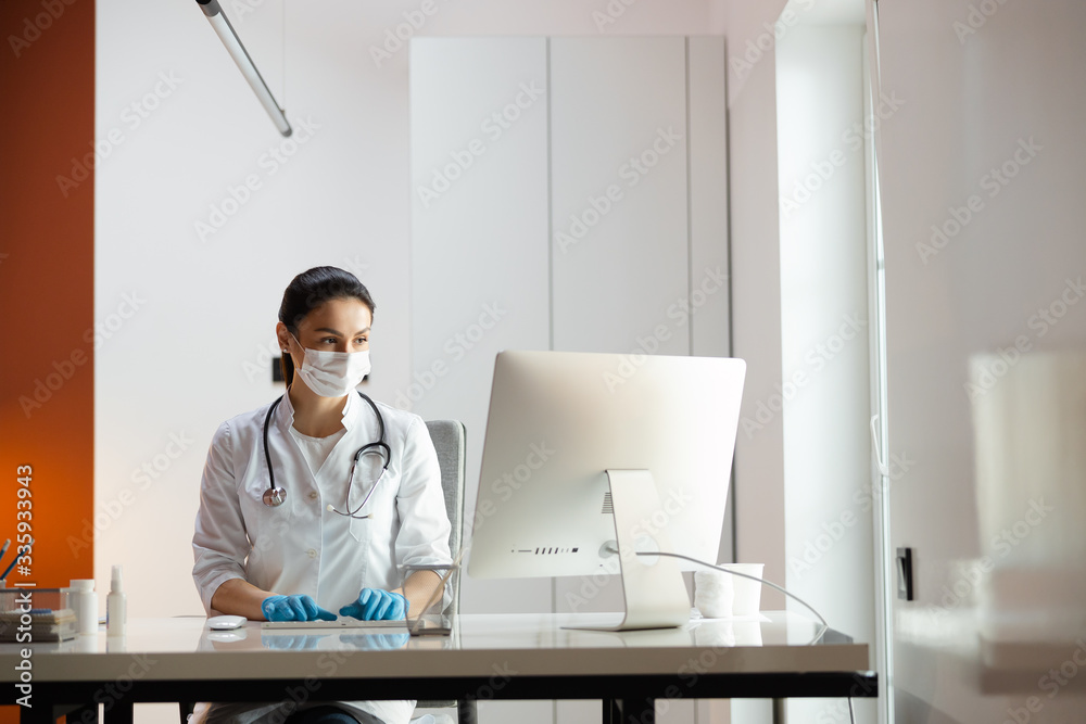 Caucasian doctor in medical mask and rubber gloves working at laptop Caucasian doctor in medical mask and rubber gloves working at laptop