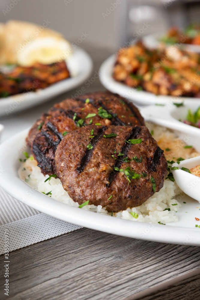 A view of several Mediterranean dishes in a restaurant or kitchen setting, featuring kafta and shish kebob. A view of several Mediterranean dishes in a restaurant or kitchen setting, featuring kafta and shish kebob.