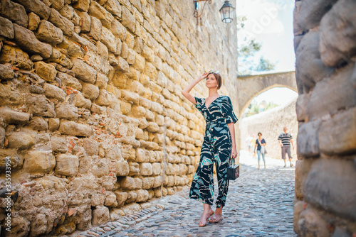 A girl in a straw hat and dress walks in Carcassonne