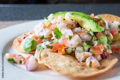 A closeup view of a plate of shrimp tostada, in a restaurant or kitchen setting. photo