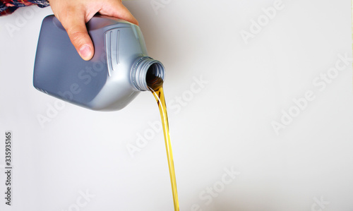 automotive oil in a hand a gray bottle on a light background