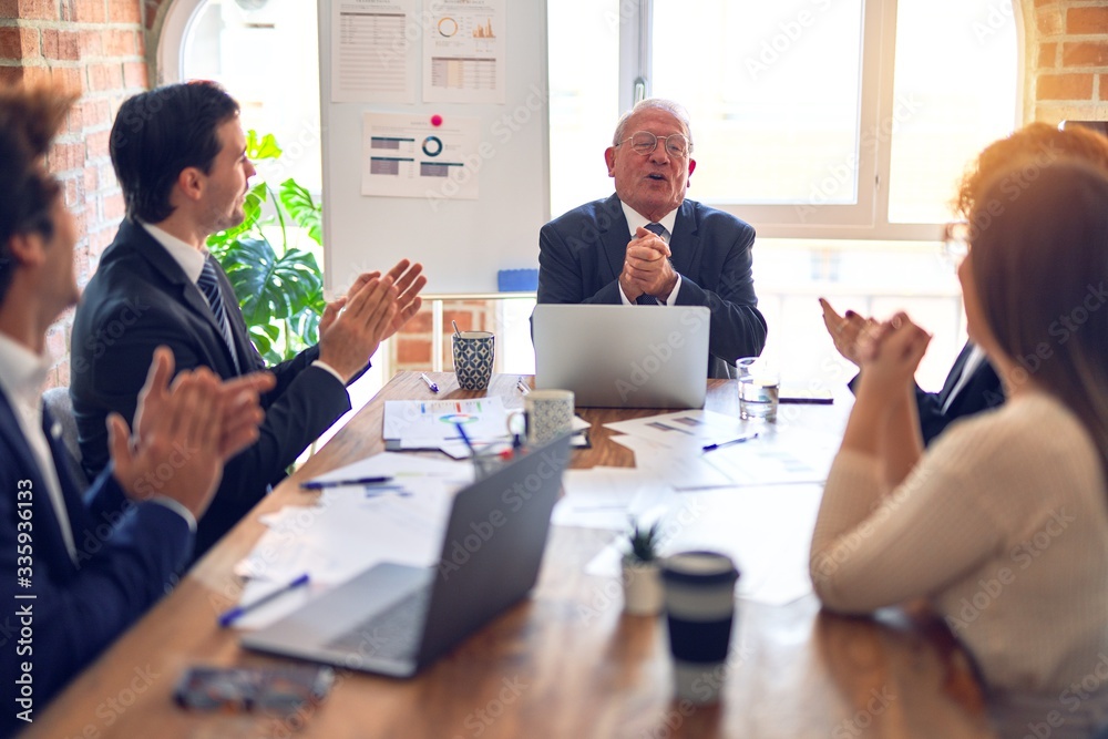 Group of business workers smiling happy and confident in a meeting. Working together looking at presentation using board and laptop applauding at the office.