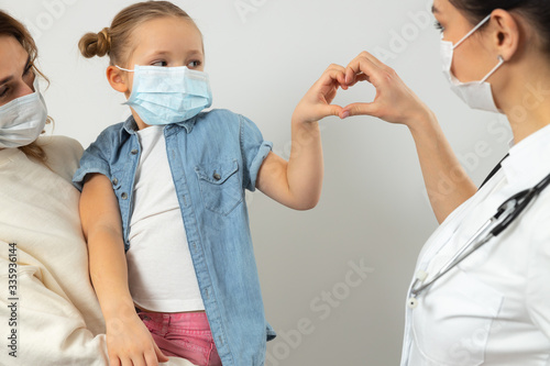 Caucasian mother and her kid wearing medical masks in clinic