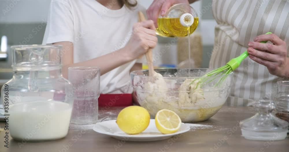 Mother and daughter child together at home kitchen kneading dough in bowl, close-up Mother and daughter child together at home kitchen kneading dough in bowl, close-up
