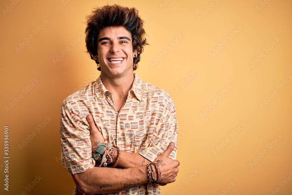 Young handsome man on vacation wearing summer shirt over isolated yellow background happy face smiling with crossed arms looking at the camera. Positive person. Young handsome man on vacation wearing summer shirt over isolated yellow background happy face smiling with crossed arms looking at the camera. Positive person.