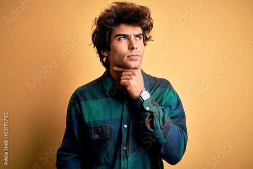 Young handsome man wearing casual shirt standing over isolated yellow background Touching painful neck, sore throat for flu, clod and infection © Krakenimages.com