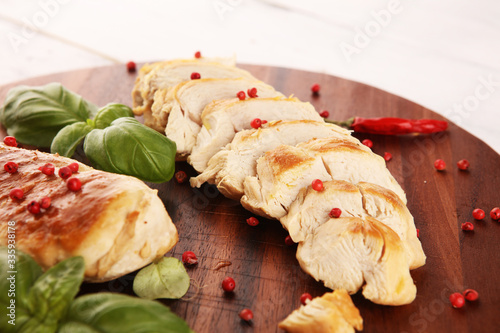 Partially sliced grilled chicken breast on cutting board on table