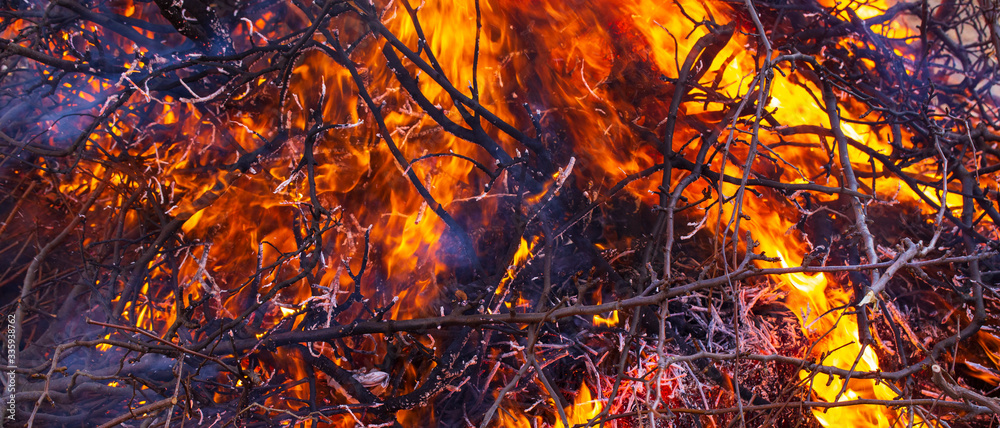 Flaming fire. Big bonfire in Shrovetide. Burning tree branches. People look at the fire. Pagan rite dedicated to the arrival of spring. Flaming fire. Big bonfire in Shrovetide. Burning tree branches. People look at the fire. Pagan rite dedicated to the arrival of spring.