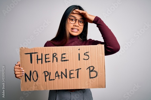 Young asian activist girl asking for environment holding banner with planet message stressed with hand on head, shocked with shame and surprise face, angry and frustrated. Fear and upset for mistake.