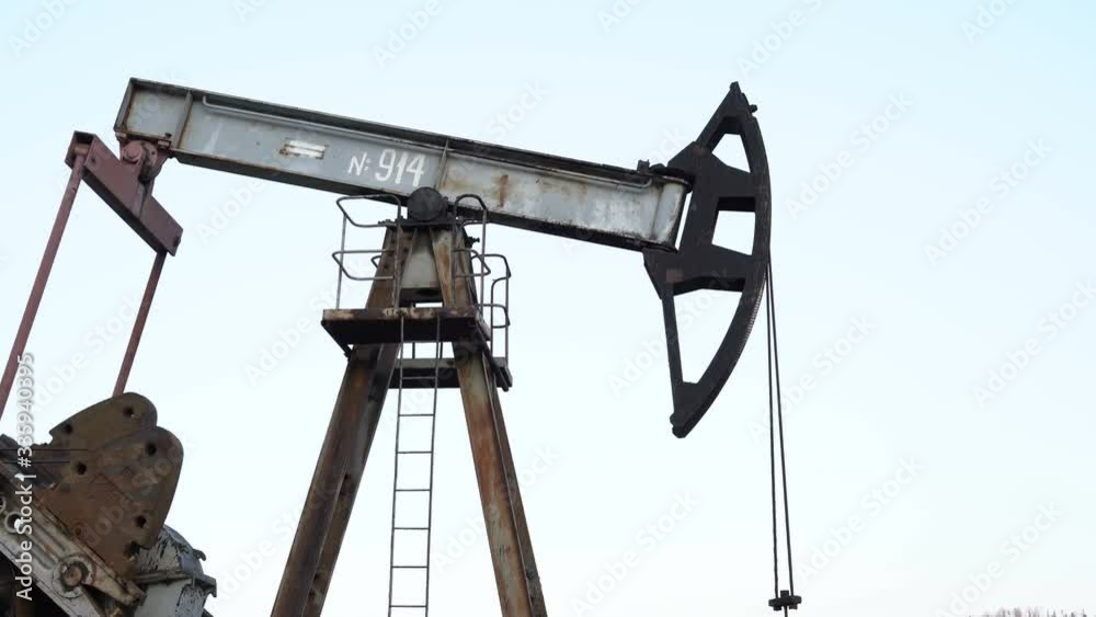 Old Oil Well Pump Jack Extracting Petroleum. Working Oil Pump Jack Against The Sky. Extraction of Petroleum. Fossil Fuel Energy. Old Oil Well Pump Jack Extracting Petroleum. Working Oil Pump Jack Against The Sky. Extraction of Petroleum. Fossil Fuel Energy.