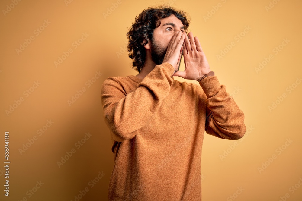 Young handsome man with beard wearing casual sweater standing over yellow background Shouting angry out loud with hands over mouth Young handsome man with beard wearing casual sweater standing over yellow background Shouting angry out loud with hands over mouth