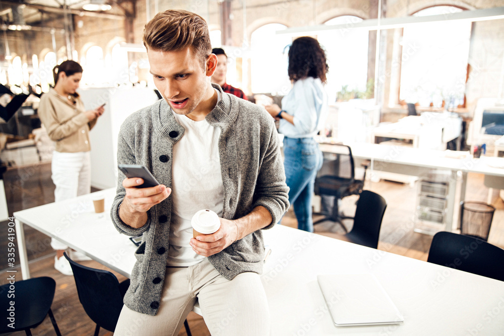 Obraz premium Amazed young man using cellphone at work