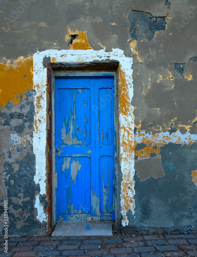 Old wooden blue painted door in a wall of an old fishing house. © Daguimagery