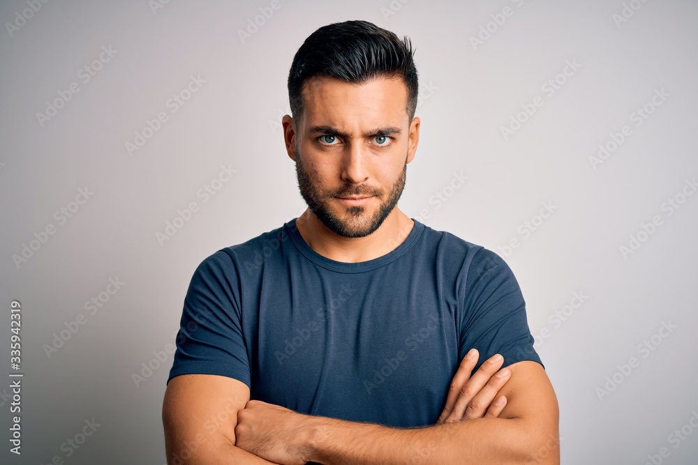 Young handsome man wearing casual t-shirt standing over isolated white background skeptic and nervous, disapproving expression on face with crossed arms. Negative person. Young handsome man wearing casual t-shirt standing over isolated white background skeptic and nervous, disapproving expression on face with crossed arms. Negative person.