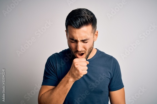 Young handsome man wearing casual t-shirt standing over isolated white background feeling unwell and coughing as symptom for cold or bronchitis. Health care concept.