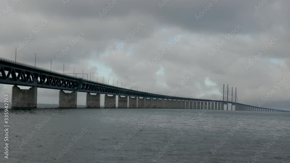 Long shot of Oresund Bridge over the sea, the borden between Sweden and Denmark with a cloudy blue sky in background Long shot of Oresund Bridge over the sea, the borden between Sweden and Denmark with a cloudy blue sky in background