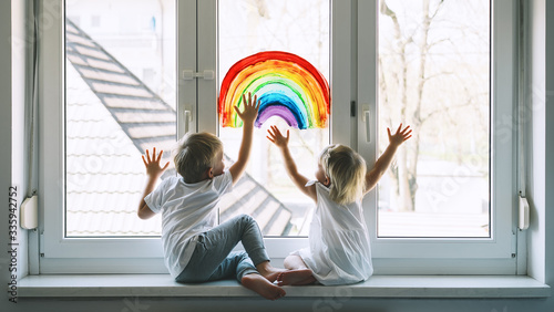 Little children on background of painting rainbow on window photo