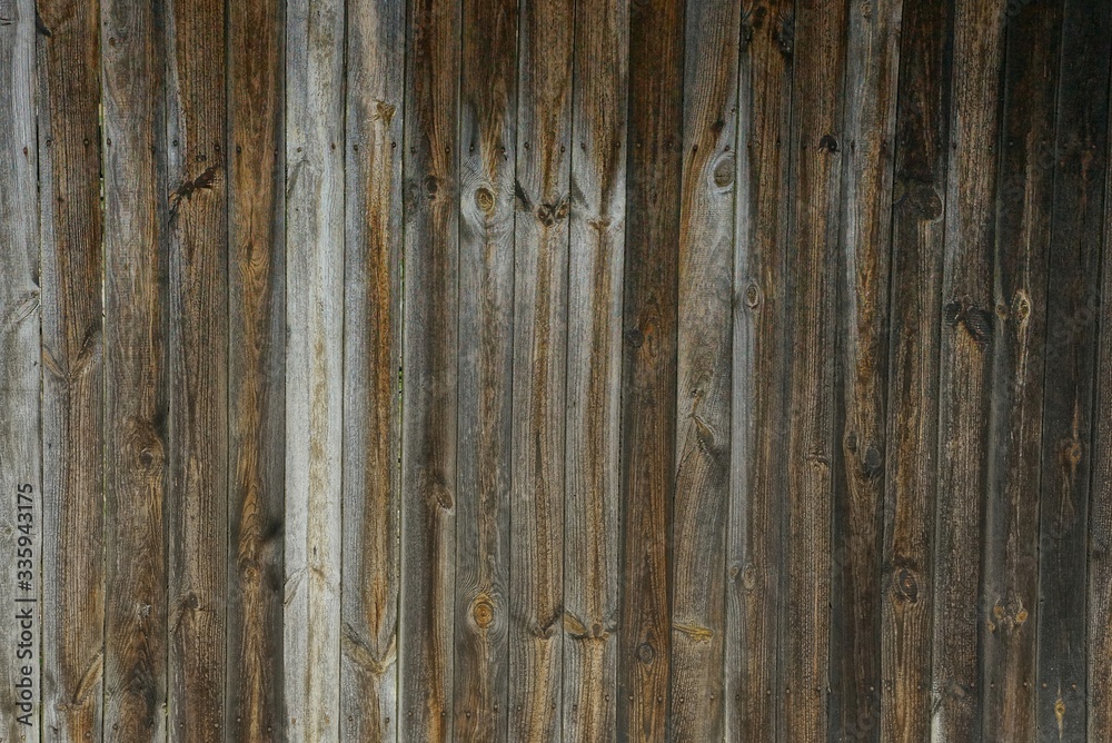 Naklejka premium dark wooden texture of gray and brown boards in the wall of the fence on the street