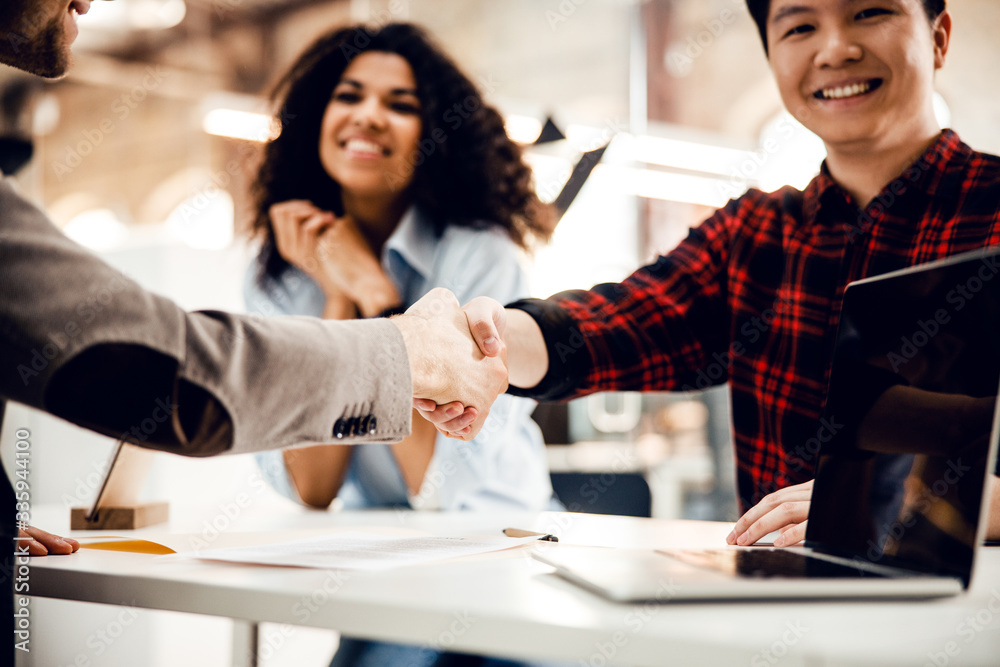 Business partners sitting at the table and shaking hands Business partners sitting at the table and shaking hands