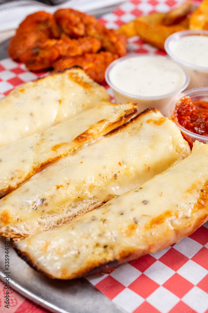 A closeup view of a sampler plate, featuring garlic cheese bread and buffalo wings, in a restaurant or kitchen setting.