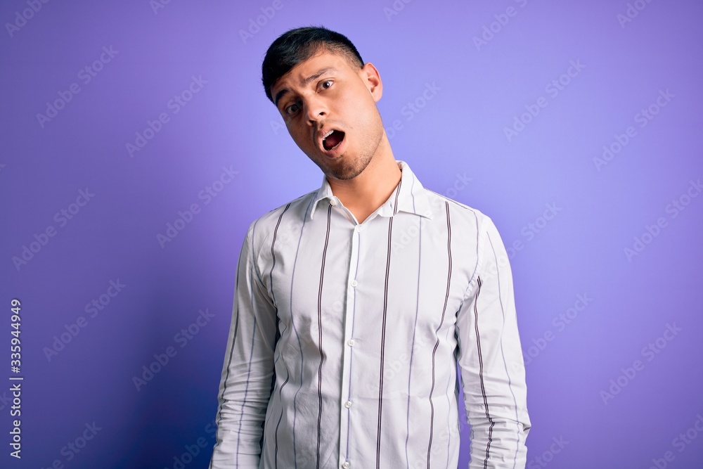 Fototapeta premium Young handsome hispanic man wearing elegant business shirt standing over purple background In shock face, looking skeptical and sarcastic, surprised with open mouth