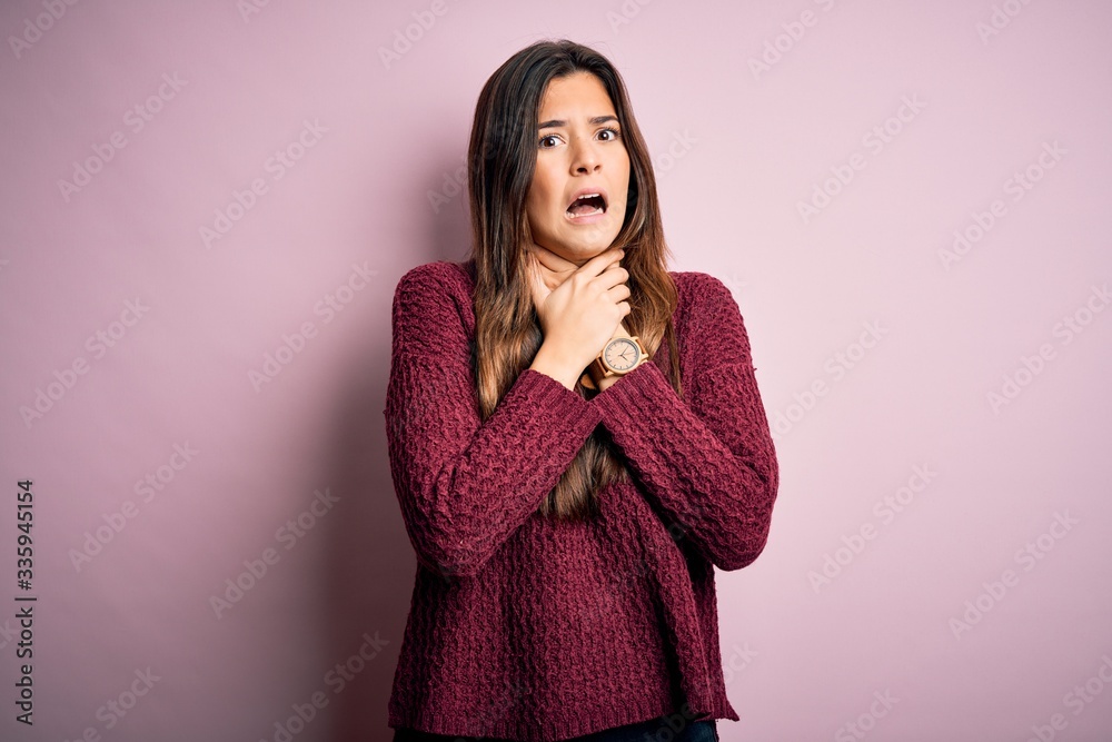 Young beautiful girl wearing casual sweater over isolated pink background shouting suffocate because painful strangle. Health problem. Asphyxiate and suicide concept. Young beautiful girl wearing casual sweater over isolated pink background shouting suffocate because painful strangle. Health problem. Asphyxiate and suicide concept.