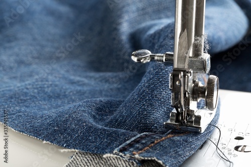 Fototapeta Blue jeans denim sewed on sewing machine close up - jeans fashion mending or rep