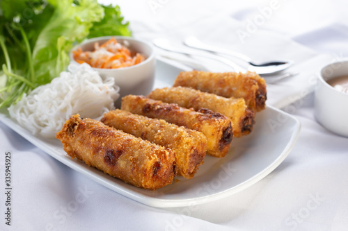 A view of an appetizer plate of egg rolls, in a restaurant or kitchen setting.