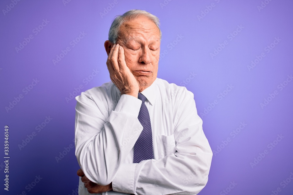 Grey haired senior business elegant man standing over purple isolated background thinking looking tired and bored with depression problems with crossed arms. Grey haired senior business elegant man standing over purple isolated background thinking looking tired and bored with depression problems with crossed arms.