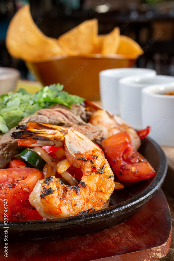 A closeup view of a prawn on a surf and turf style fajita skillet plate, in a restaurant or kitchen setting. A closeup view of a prawn on a surf and turf style fajita skillet plate, in a restaurant or kitchen setting.