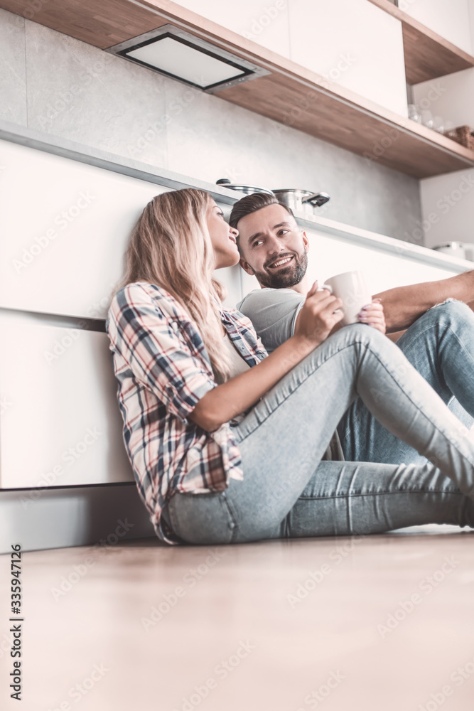 Fototapeta premium young couple drinking coffee sitting on the kitchen floor