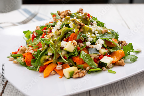 A view of a Mediterranean spinach and roasted veggie garden salad, in a restaurant or kitchen setting.