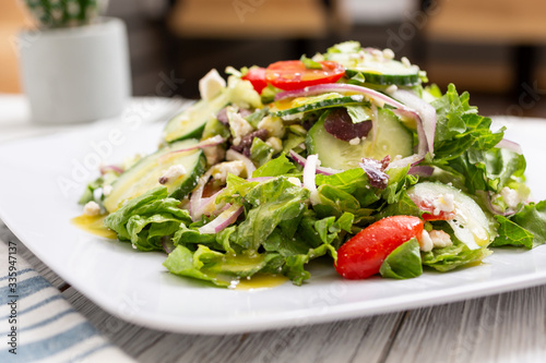 A view of a Greek garden salad, in a restaurant or kitchen setting.