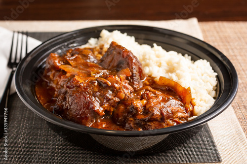 Obraz na plátne A view of a bowl of oxtail stew with white rice, in a restaurant or kitchen setting