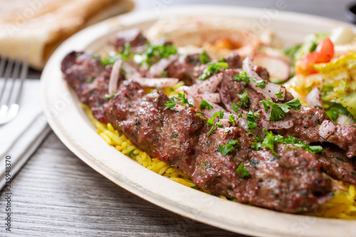 A closeup view of a plate of kabab koobideh, in a restaurant or kitchen setting.
