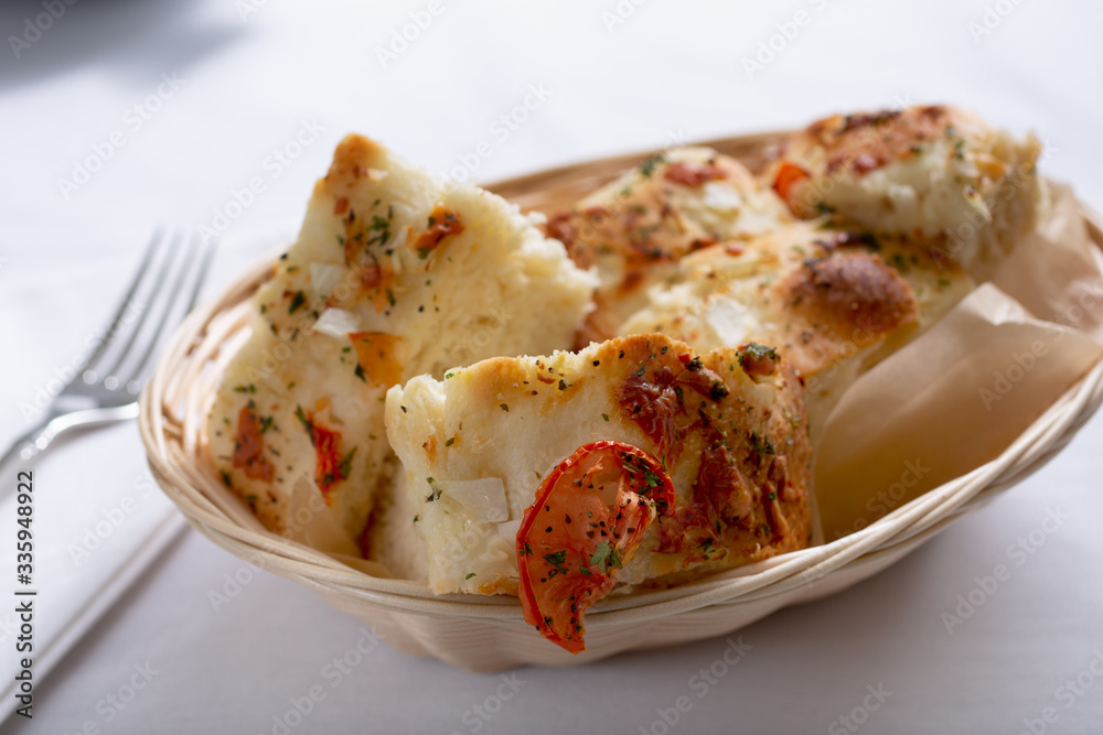 A view of a basket of focaccia bread in a restaurant or kitchen setting. A view of a basket of focaccia bread in a restaurant or kitchen setting.