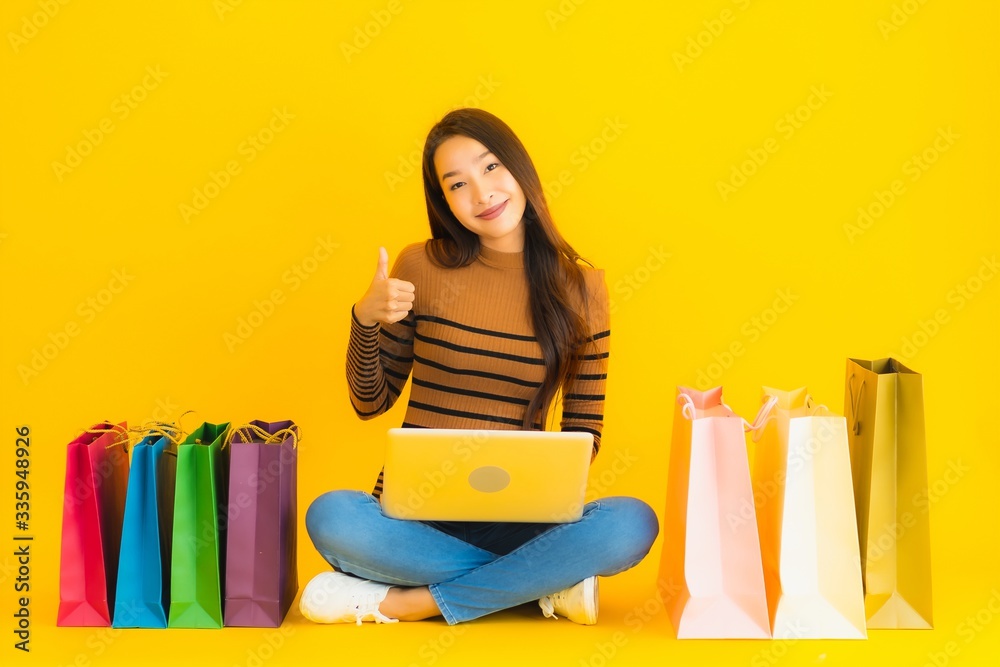 Beautiful portrait young asian woman sit on the floor with laptop or computer use credit card for online shopping around shopping bag Beautiful portrait young asian woman sit on the floor with laptop or computer use credit card for online shopping around shopping bag