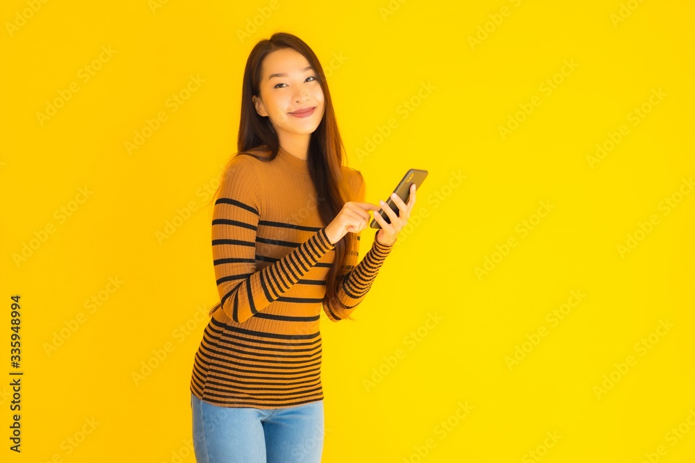 Beautiful young asian woman use smart mobile phone or cellphone with many action on yellow background Beautiful young asian woman use smart mobile phone or cellphone with many action on yellow background