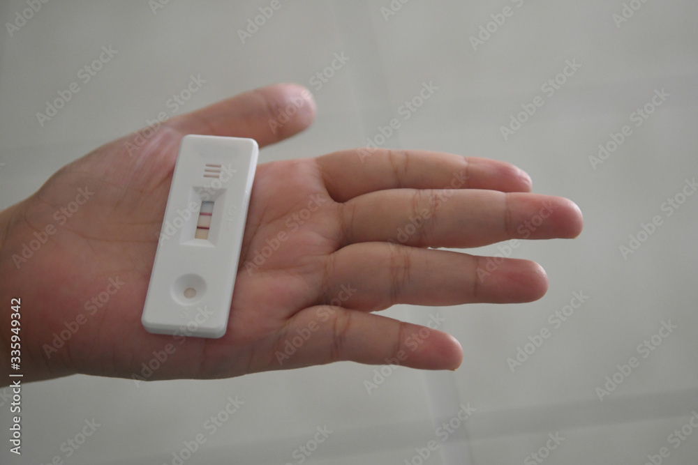 Close up pregnancy test in female hand on with positive pregnant on blurred background.