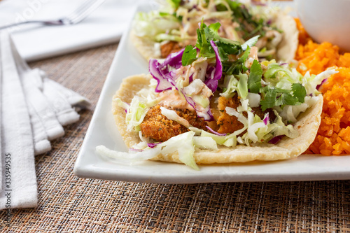 A closeup view of a fish tacos plate, in a restaurant or kitchen setting.