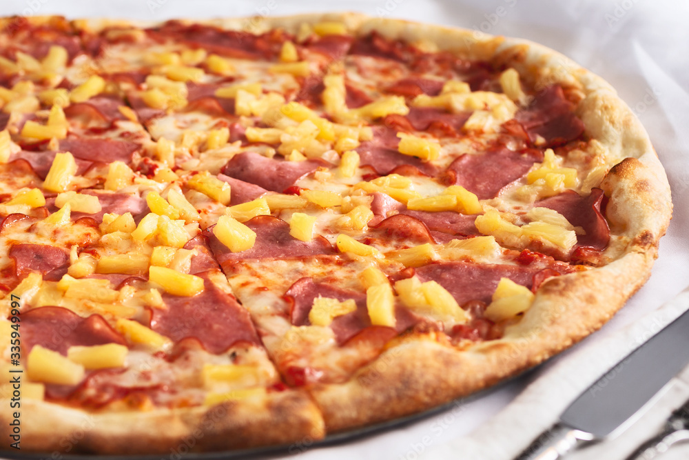 A view of a Hawaiian pizza pie, in a restaurant or kitchen setting.