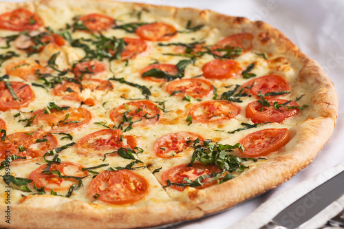 A view of a margherita pizza pie, in a restaurant or kitchen setting.