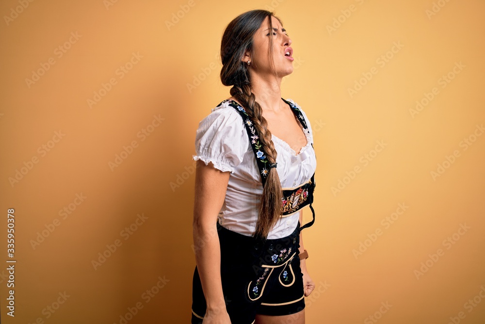 Young beautiful brunette german woman celebrating Octoberfest wearing traditional dress angry and mad screaming frustrated and furious, shouting with anger. Rage and aggressive concept. Young beautiful brunette german woman celebrating Octoberfest wearing traditional dress angry and mad screaming frustrated and furious, shouting with anger. Rage and aggressive concept.