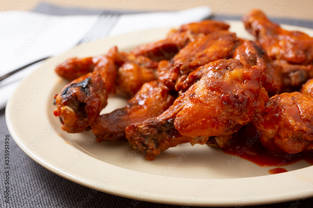 A view of a plate of buffalo wings, in a restaurant or kitchen setting.