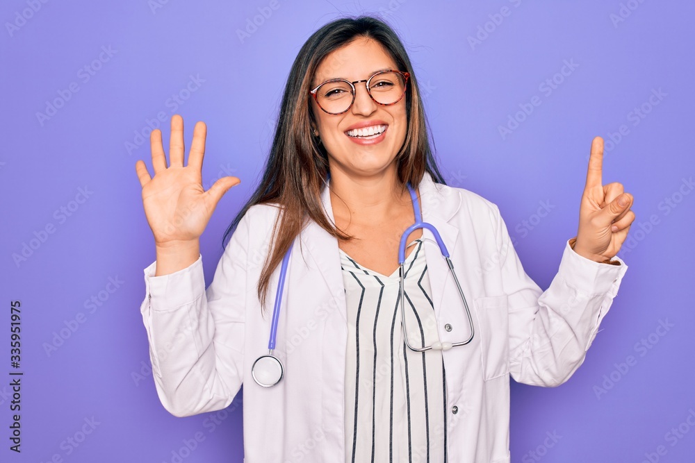 Professional doctor woman wearing stethoscope and medical coat over purple background showing and pointing up with fingers number six while smiling confident and happy. Professional doctor woman wearing stethoscope and medical coat over purple background showing and pointing up with fingers number six while smiling confident and happy.