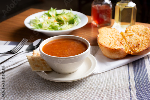 A view of a soup and salad meal in a restaurant or kitchen setting, featuring garlic bread.