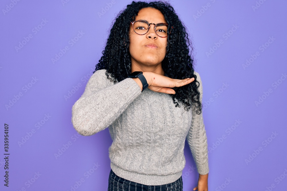 Young african american woman wearing casual sweater and glasses over purple background cutting throat with hand as knife, threaten aggression with furious violence