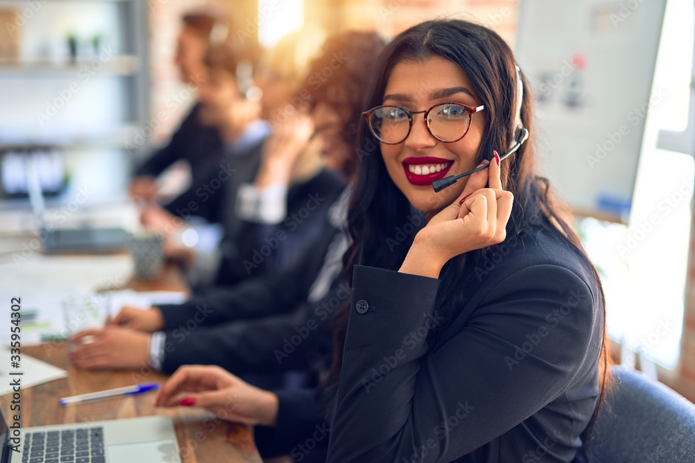 Group of call center workers working together with smile on face using headset. Young beautiful woman smiling at the office. Group of call center workers working together with smile on face using headset. Young beautiful woman smiling at the office.