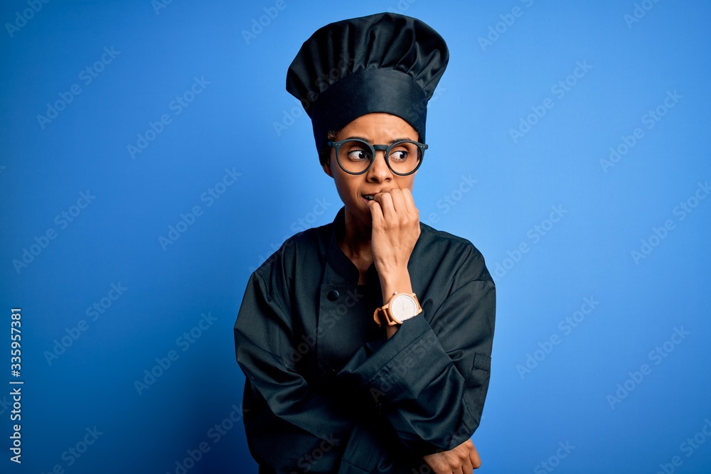 Young african american chef woman wearing cooker uniform and hat over blue background looking stressed and nervous with hands on mouth biting nails. Anxiety problem. Young african american chef woman wearing cooker uniform and hat over blue background looking stressed and nervous with hands on mouth biting nails. Anxiety problem.